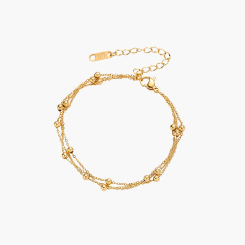 Three-strand gold-plated bracelet with clustered ball beads and adjustable clasp on cream background