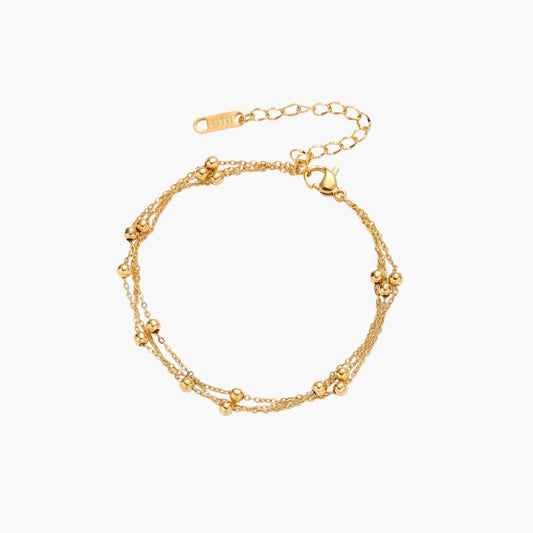 Three-strand gold-plated bracelet with clustered ball beads and adjustable clasp on cream background