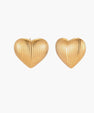 Gold heart-shaped stud earrings with parallel ridged texture on cream background