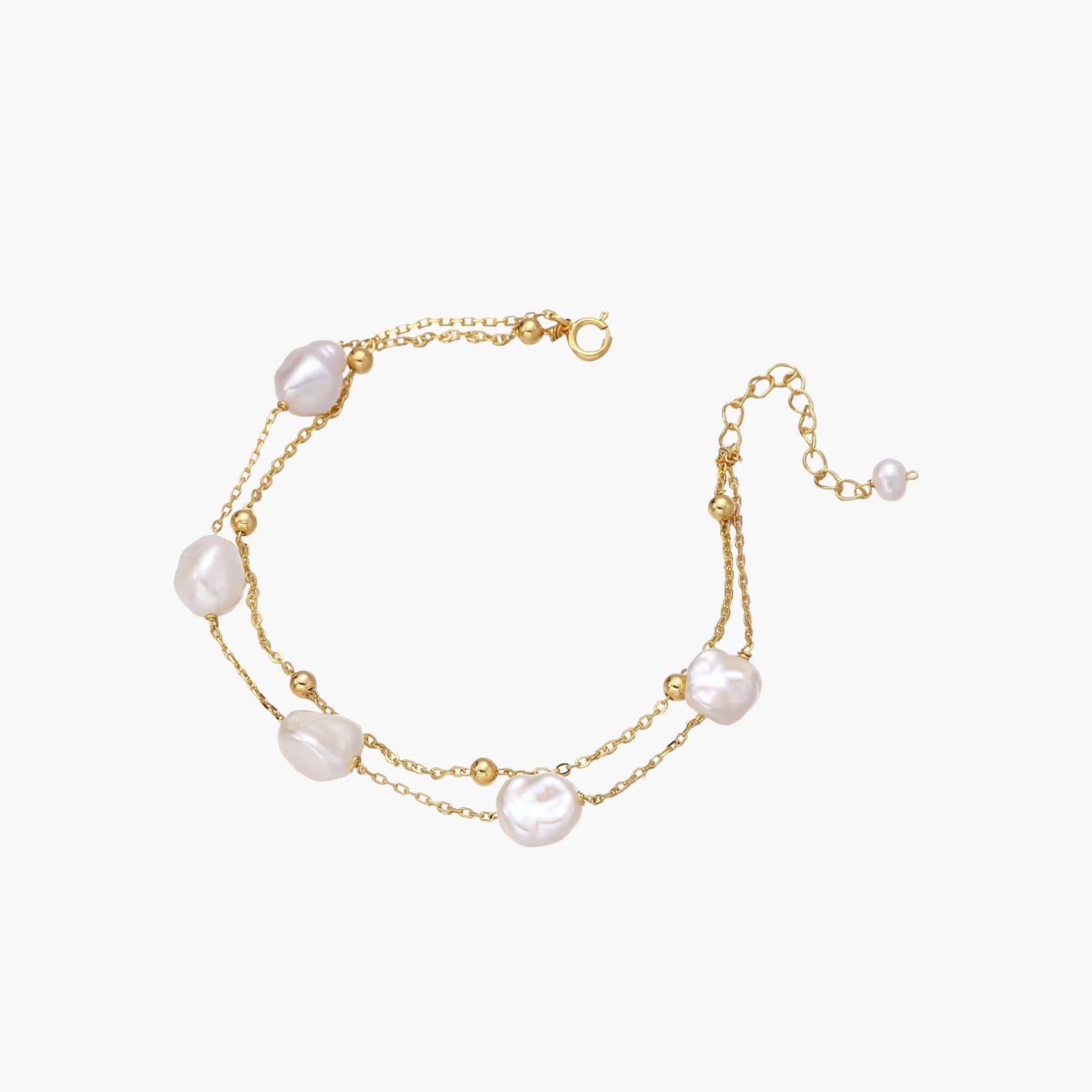 Double-strand gold bracelet with irregular baroque pearls and smooth freshwater pearls on cream background.
