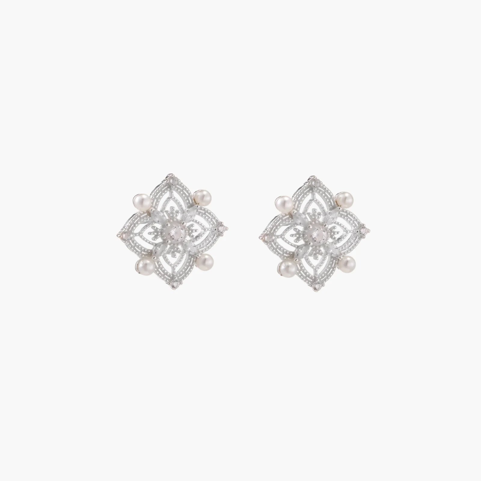 Ornate sterling silver stud earrings with mandala-inspired filigree pattern and four freshwater pearls on beige background