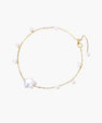 Delicate gold chain bracelet with baroque pearl centerpiece and small freshwater pearls on cream background.
