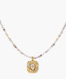 Ornate gold-plated pendant necklace with multicolored gemstone beads in purple, pink and clear tones on white background