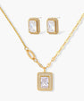 Gold-plated jewelry set with rectangular cubic zirconia stones in pave halo settings on cream background